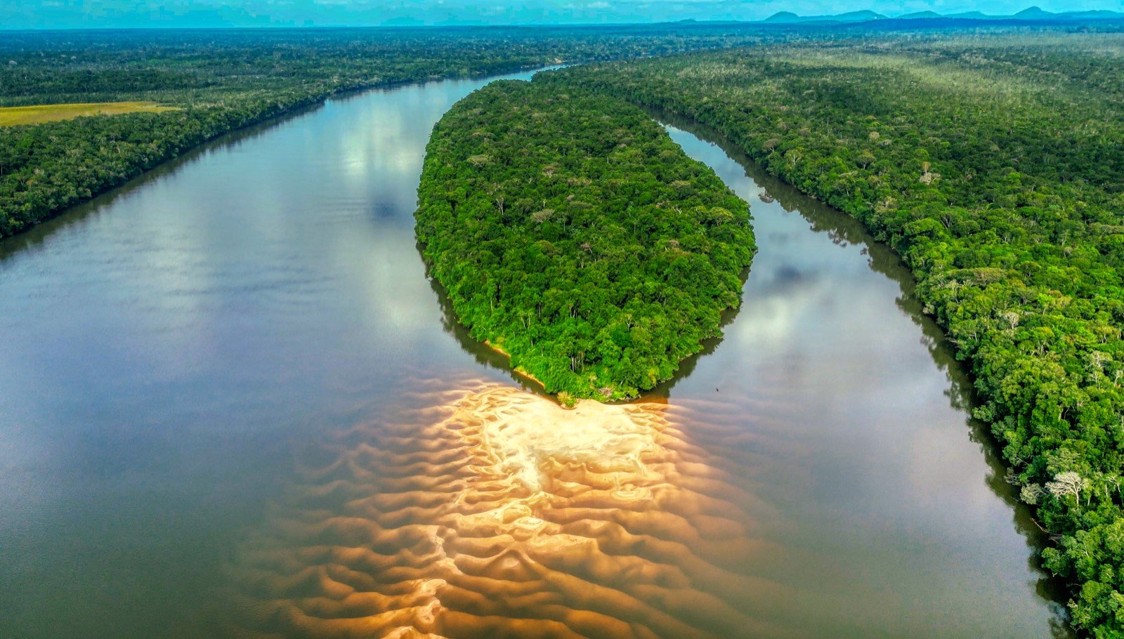 Aerial view of a broad river curving around a forested island in the Colombian Amazon